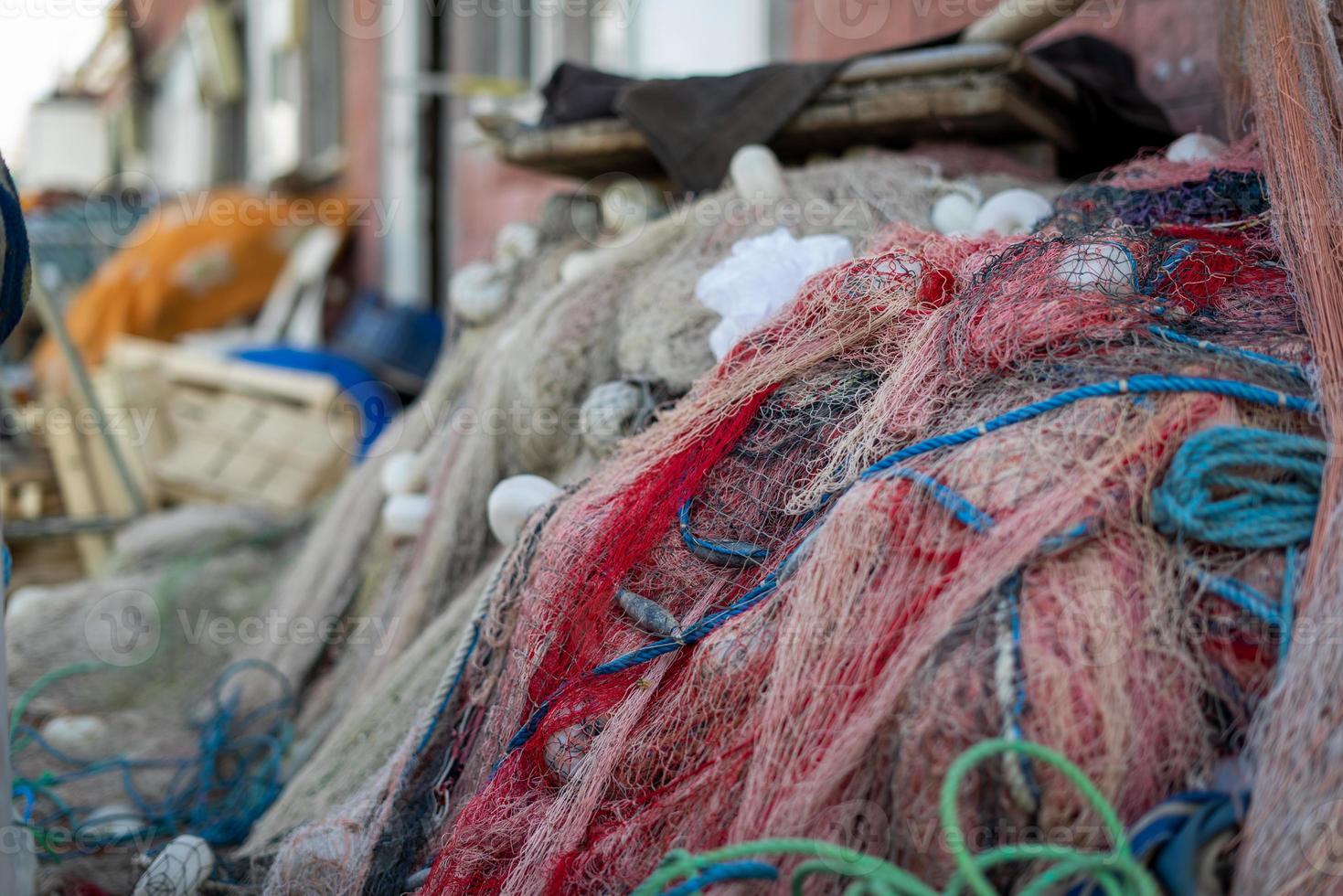 redes de pesca apiladas y cuerdas rojas, verdes, azules y blancas foto