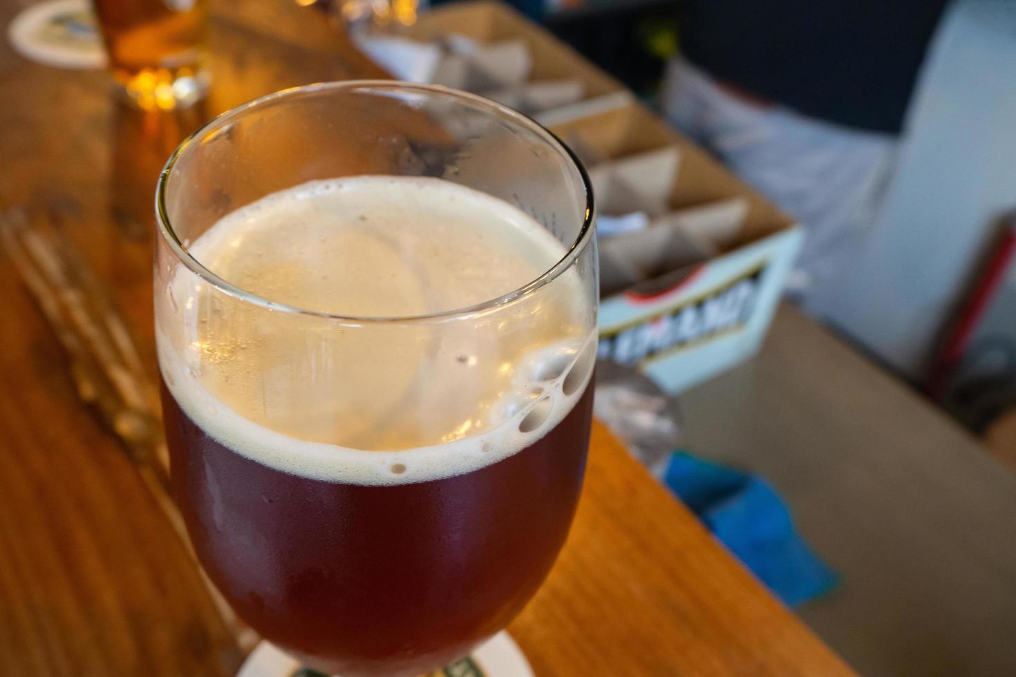 primer plano de un vaso de cerveza colocado sobre una mesa de madera en un restaurante foto