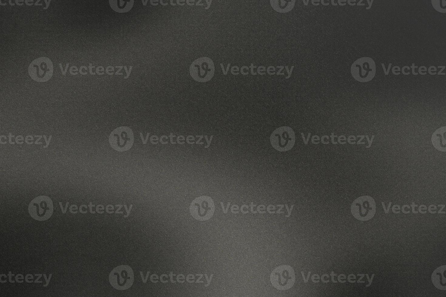 Black grunge metal wall with light shining through in dark room, abstract background photo