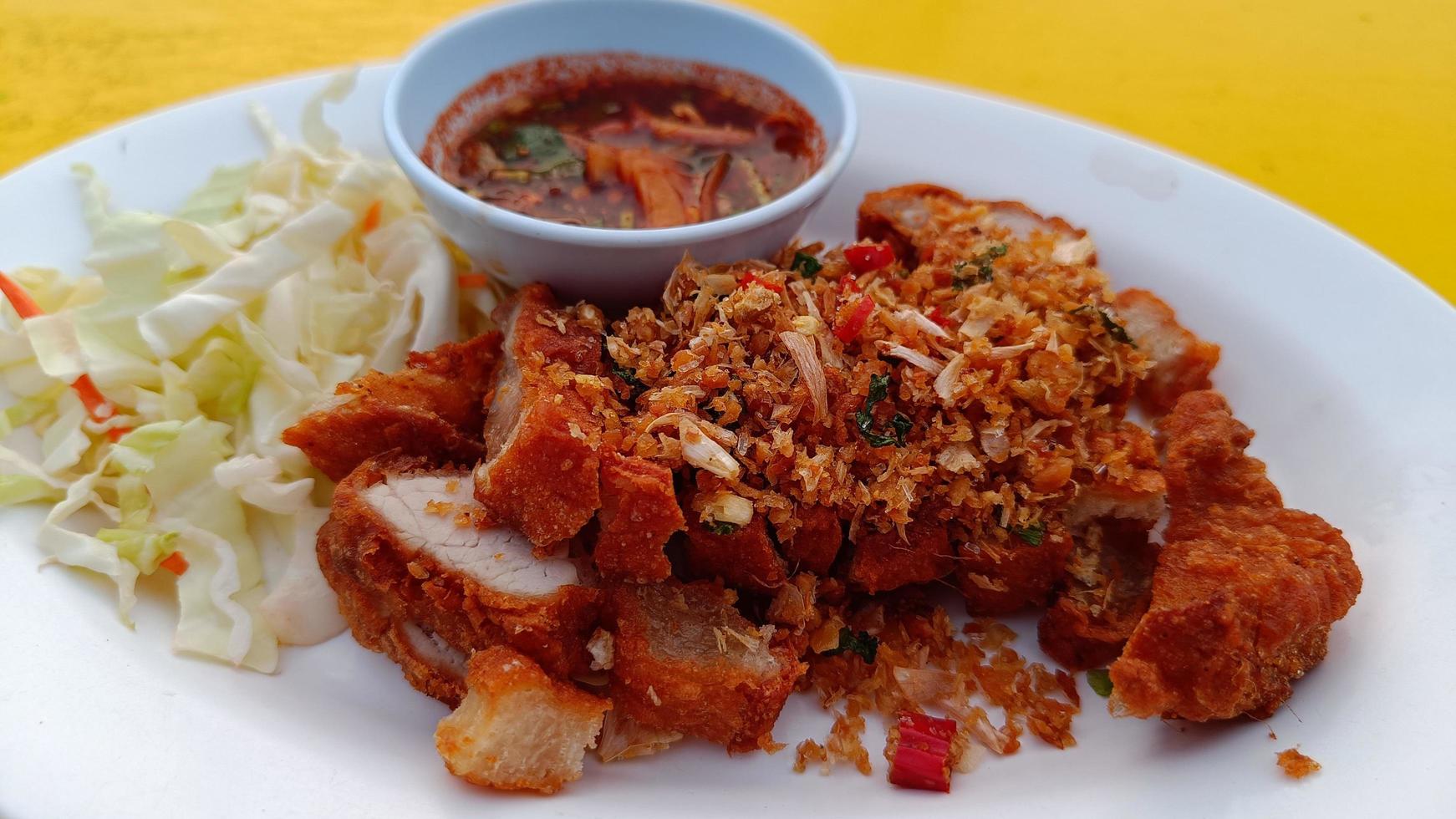 Deep fried pork belly with fish sauce on a white plate with dipping spicy sauce photo