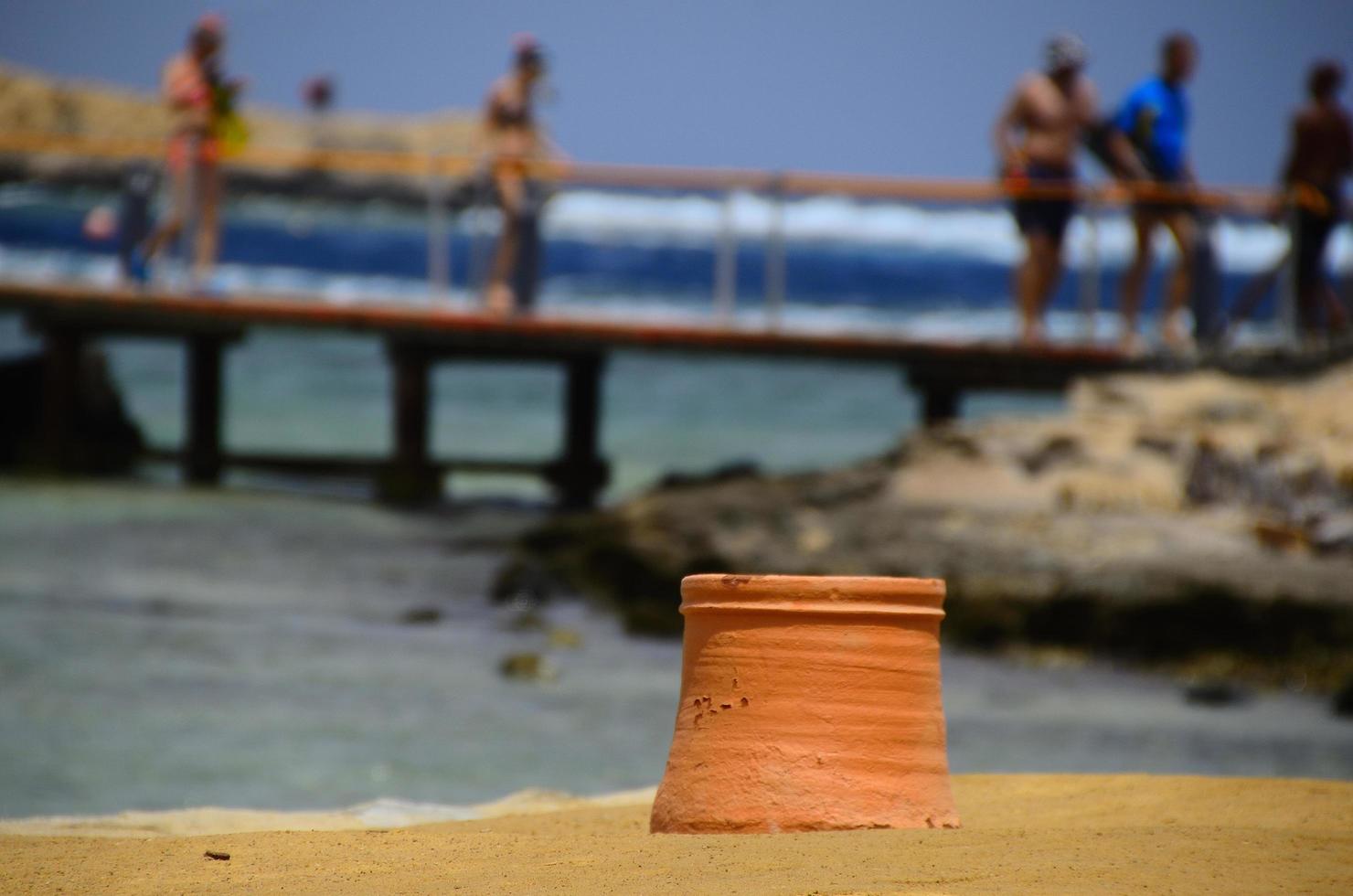 sandy beach with people on jetty in background photo