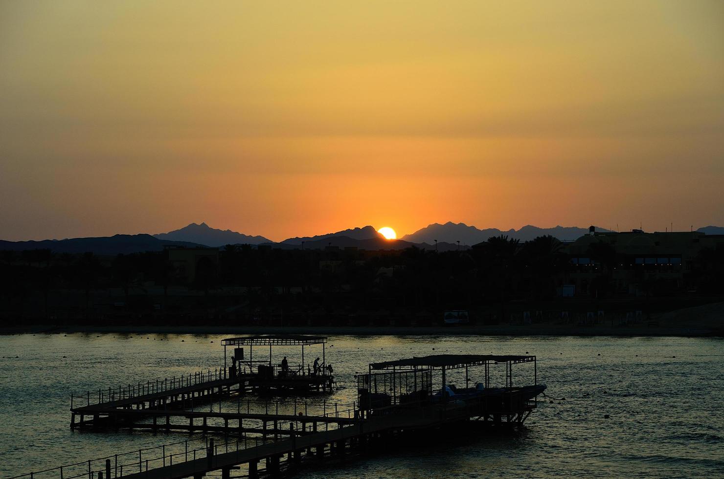 sunset at sea with pier and mountains photo