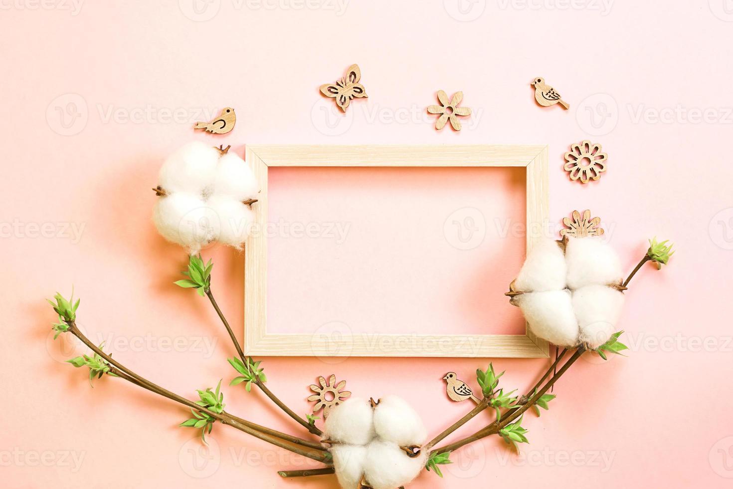 marco hecho de flores de algodón, delicadas hojitas de capullos abiertos en ramas-brotes sobre un fondo rosa y mariposas de madera tallada, pájaros, adornos. primavera, vida nueva, ternura. copie el espacio foto