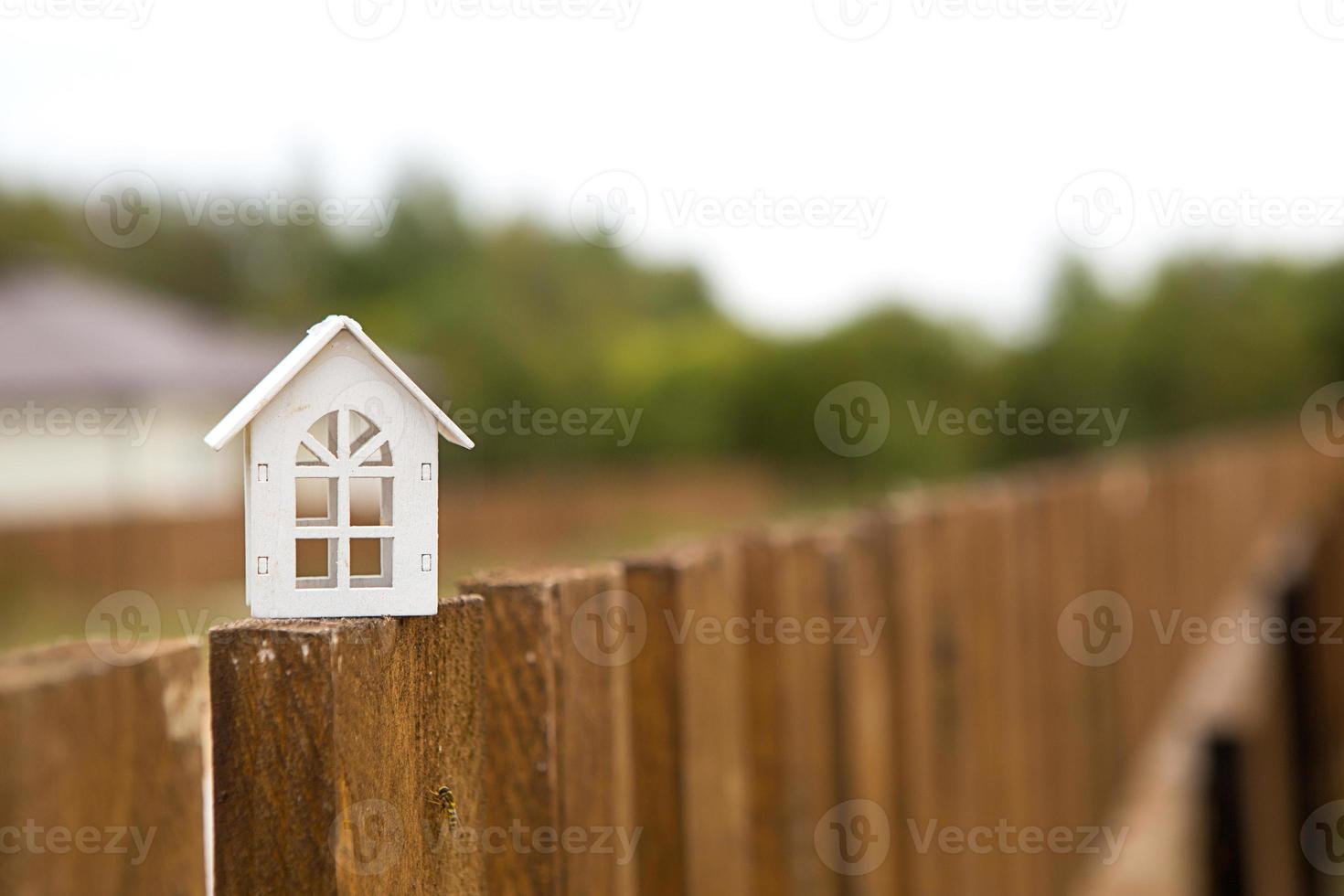 pequeña figura de casa de madera blanca en la cerca con llave para la vivienda en el fondo de las cabañas. construcción, diseño, proyecto, mudanza a casa nueva, hipoteca, alquiler y compra de bienes inmuebles. copie el espacio foto