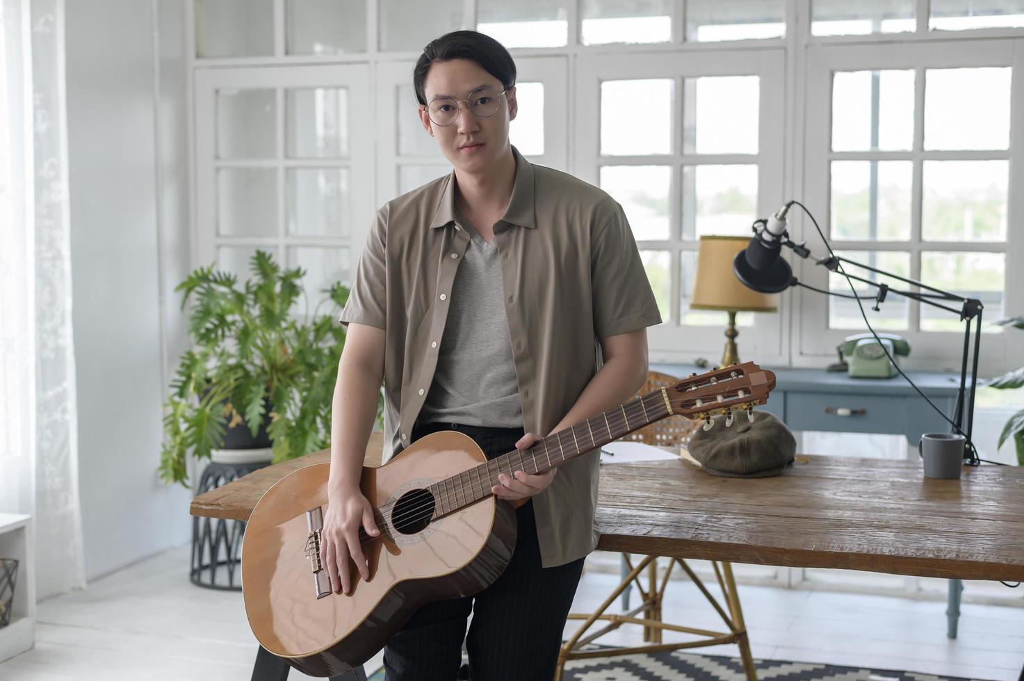 Portrait of a musician man holding guitar in home Studio photo