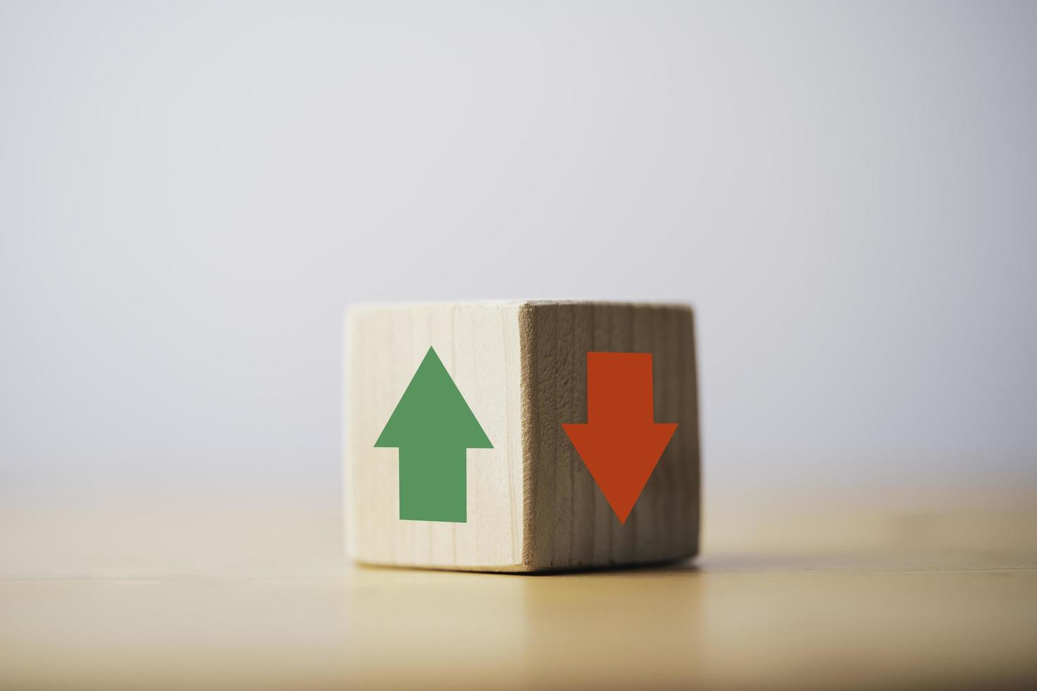 Focus of green up arrow in bright side and red down arrow in dark side which print screen on wooden cube block for economic and business profit growth concept. photo