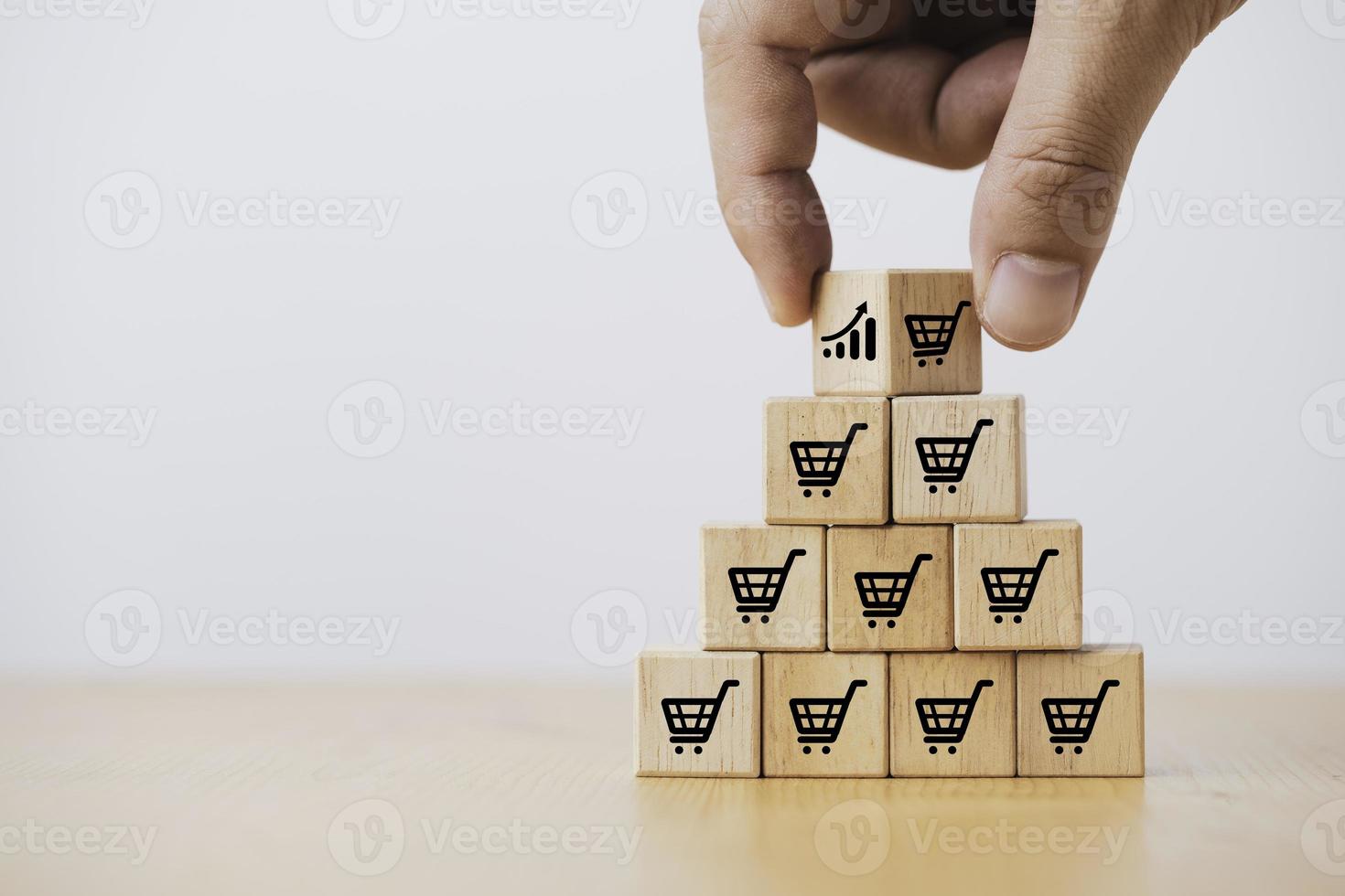 mano que sostiene el apilamiento de bloques de cubos de madera que imprimen el carrito de la compra de la pantalla y el gráfico de inversión para el aumento de la cantidad de venta y el concepto de crecimiento del negocio. foto