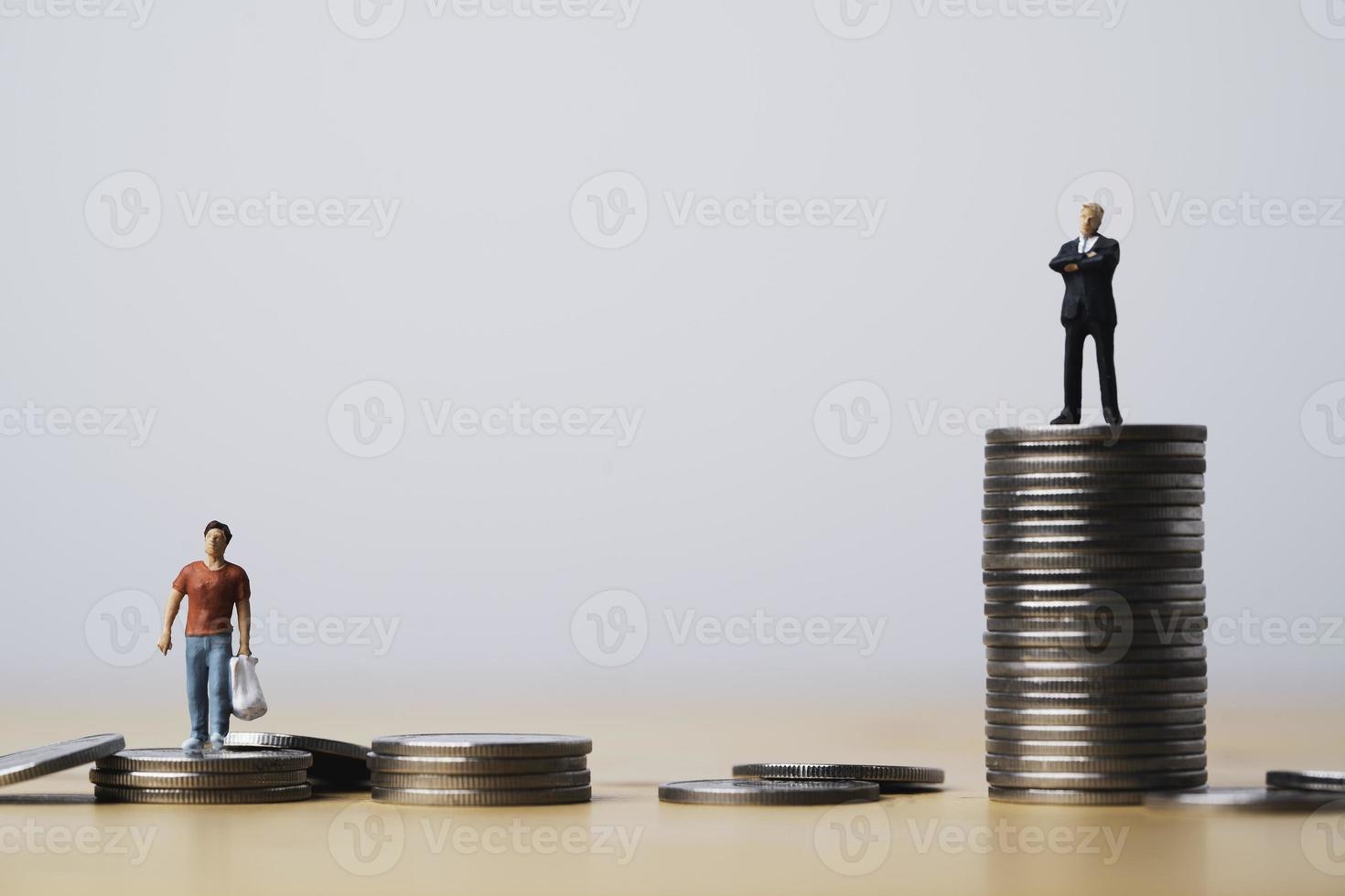 One man standing on higher coins stacking in other man for different salary and unequal income in capitalism country concept. photo