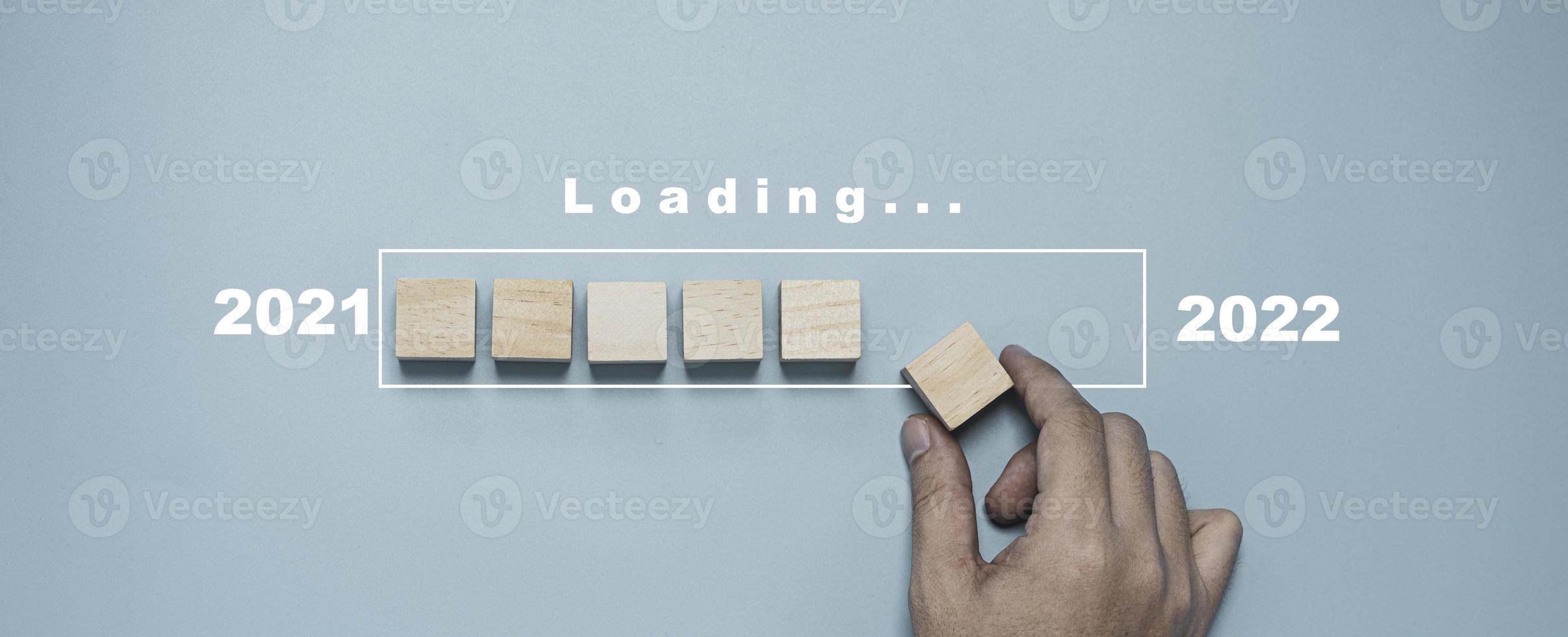 Hand putting wooden block for loading symbol of 2021 to 2022 progress and countdown merry Christmas happy new year concept. photo