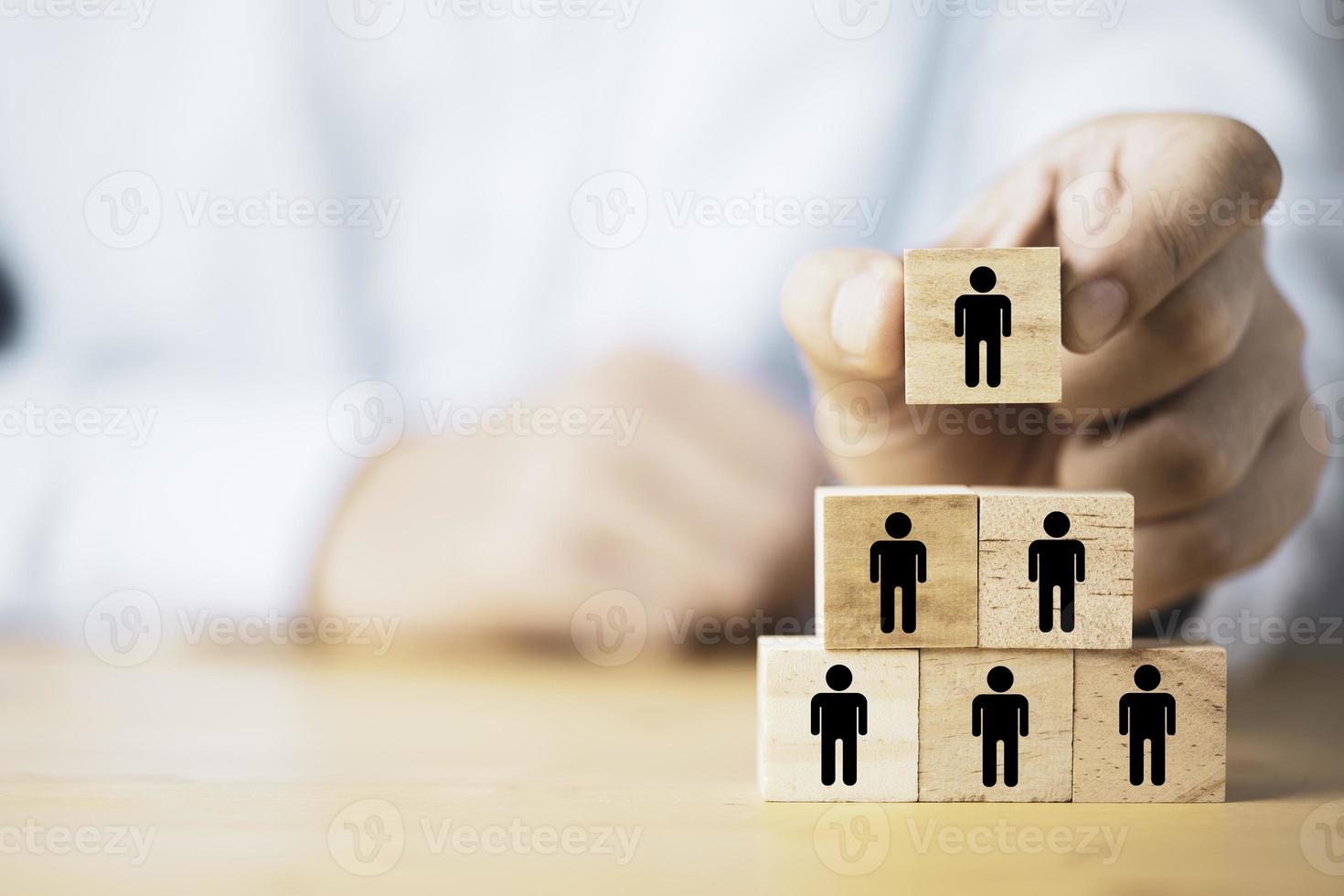 hombre de negocios sosteniendo y apilando bloques de cubos de madera que imprimen el icono humano de la pantalla para el trabajo en equipo deportivo y el concepto de corporación empresarial. foto