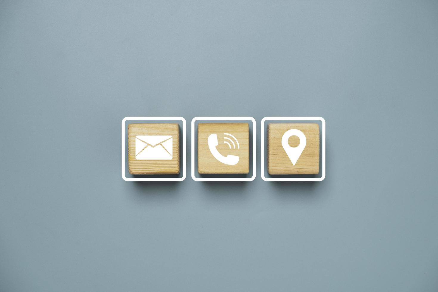 White letter telephone and location icons print screen on wooden cube block for customer service contact concept. photo