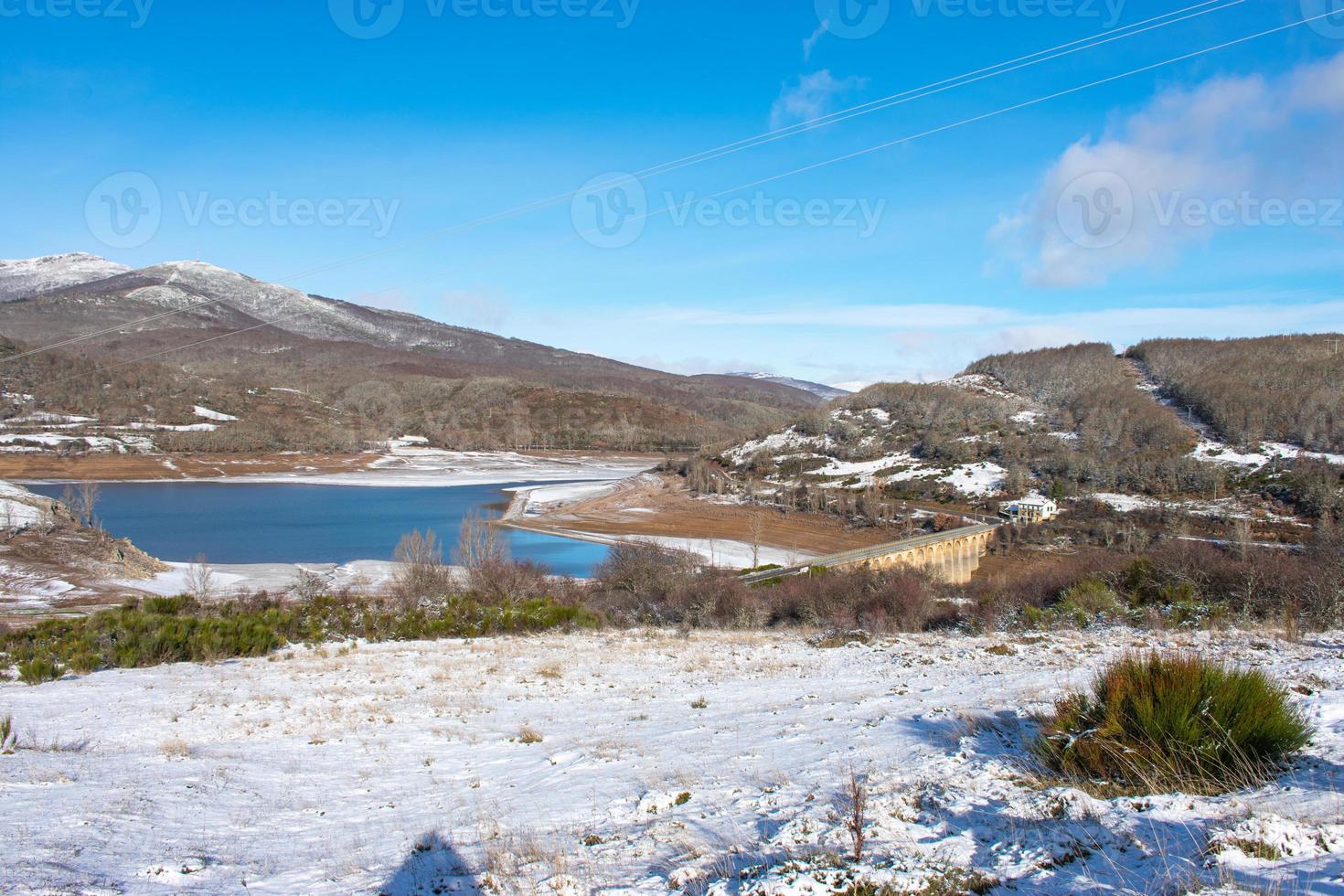 snowy mountain landscape with lake and bridge photo