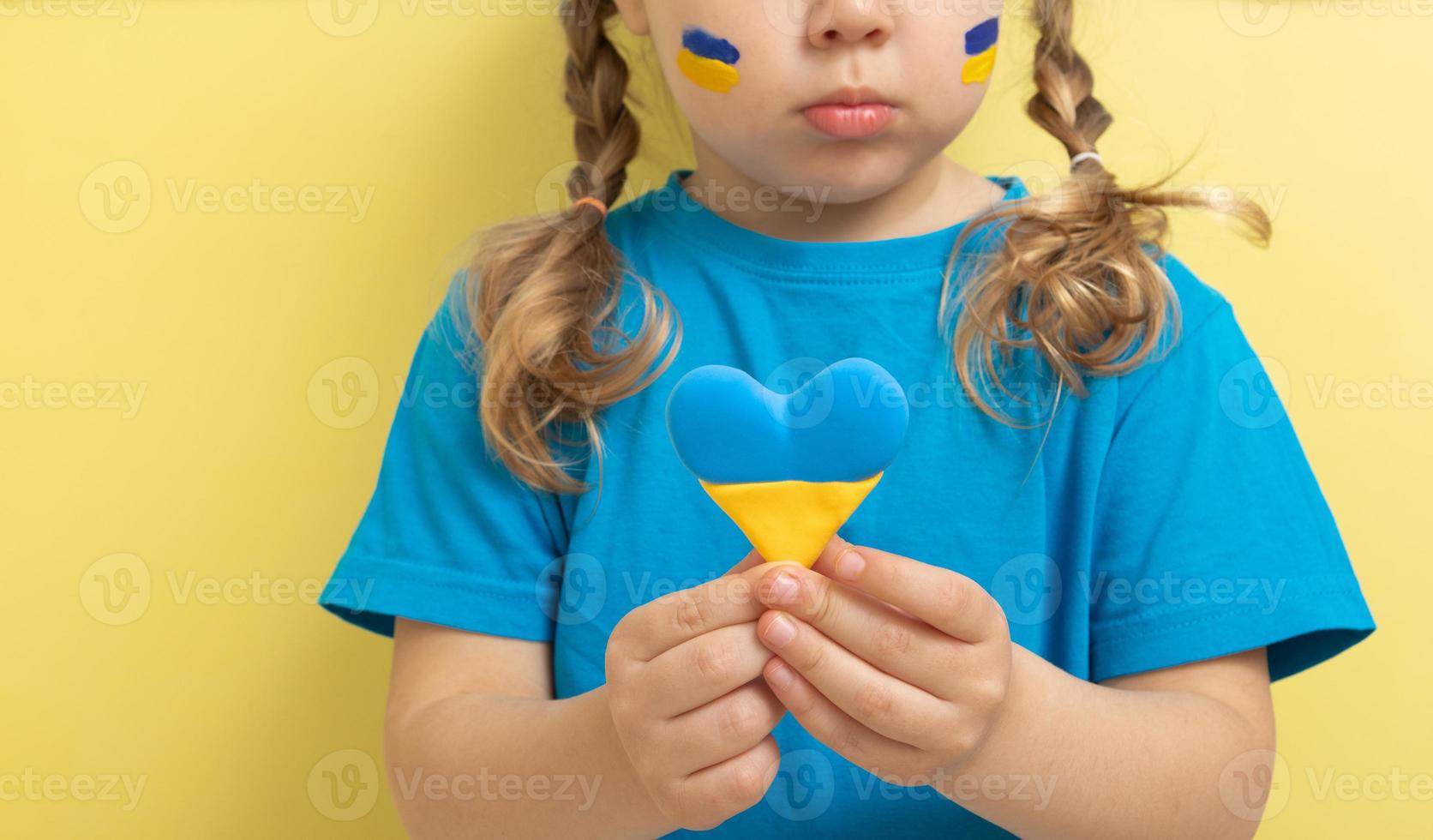 The girl holds a heart of yellow and blue color of the Ukrainian flag photo