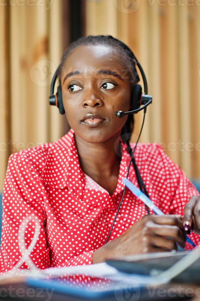 African american woman works in a call center operator and customer service agent wearing microphone headsets working on laptop. photo