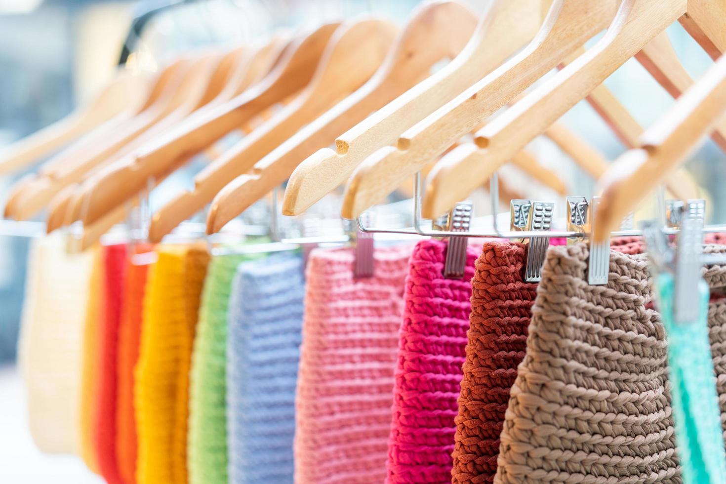 a lot of multi-colored knitwear on a rack in the showroom. Background of knitted things of different colors. The texture of knitted clothing. Handmade work and home hobbies. photo