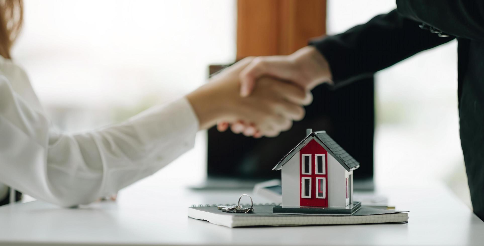 construction worker shaking hands with customer after finishing up business meeting to start up project contract in office center at construction site behind house model, home loan contract concept photo