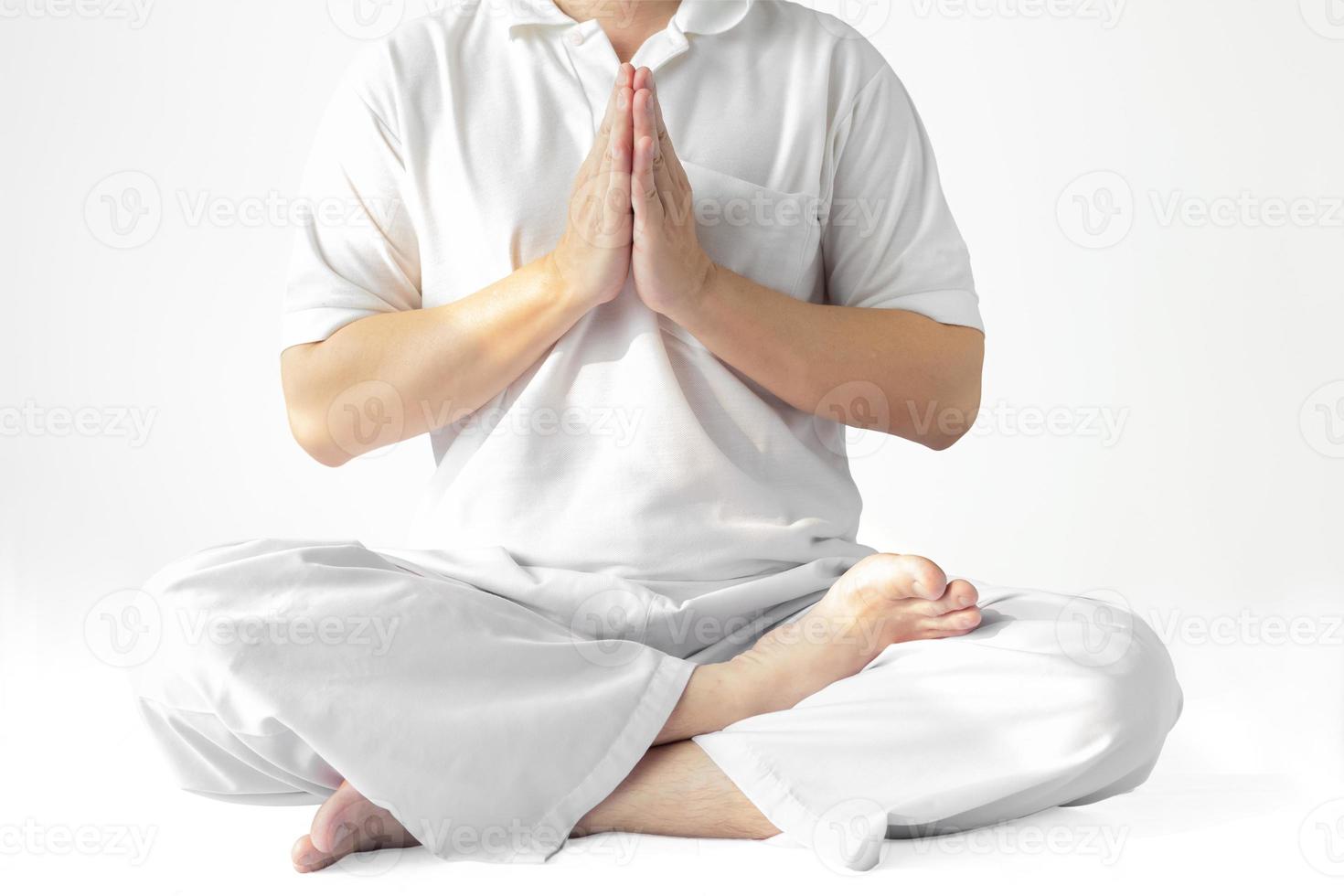 un hombre con una túnica blanca meditando sobre un fondo blanco con un sendero recortado. foto