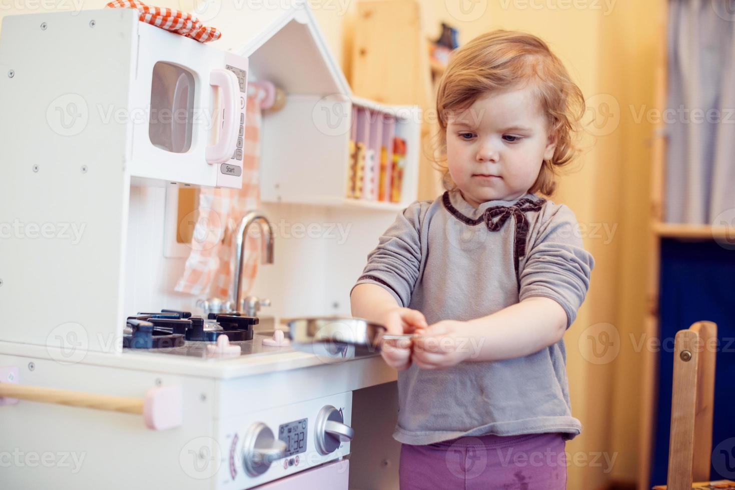 toddler girl playing toy kitchen photo