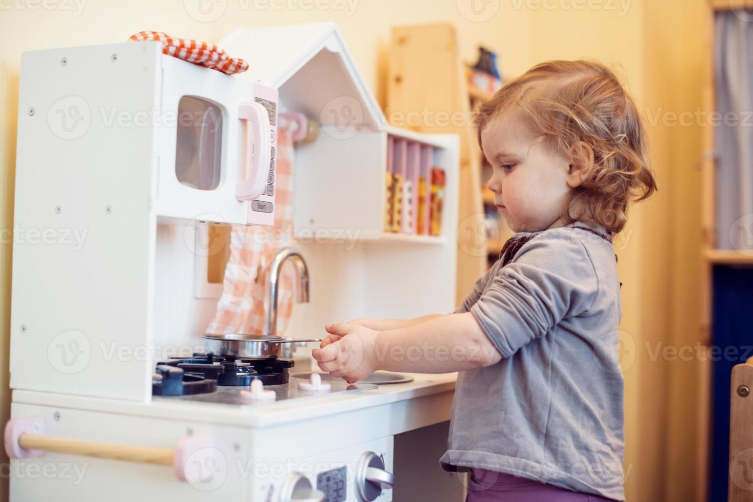 toddler girl playing toy kitchen photo