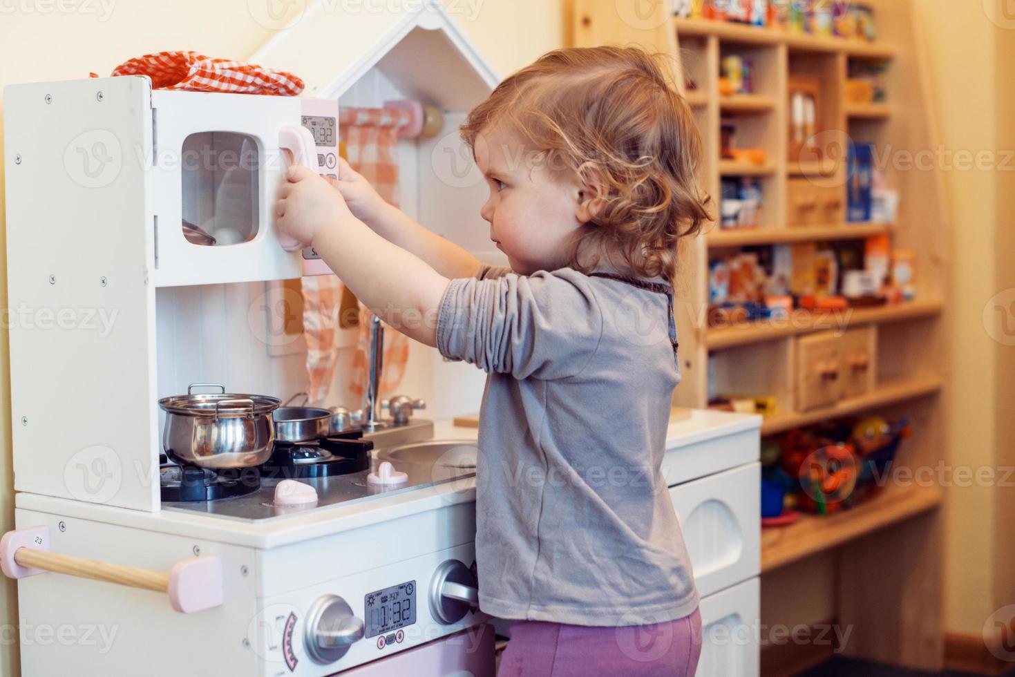 toddler girl playing toy kitchen photo