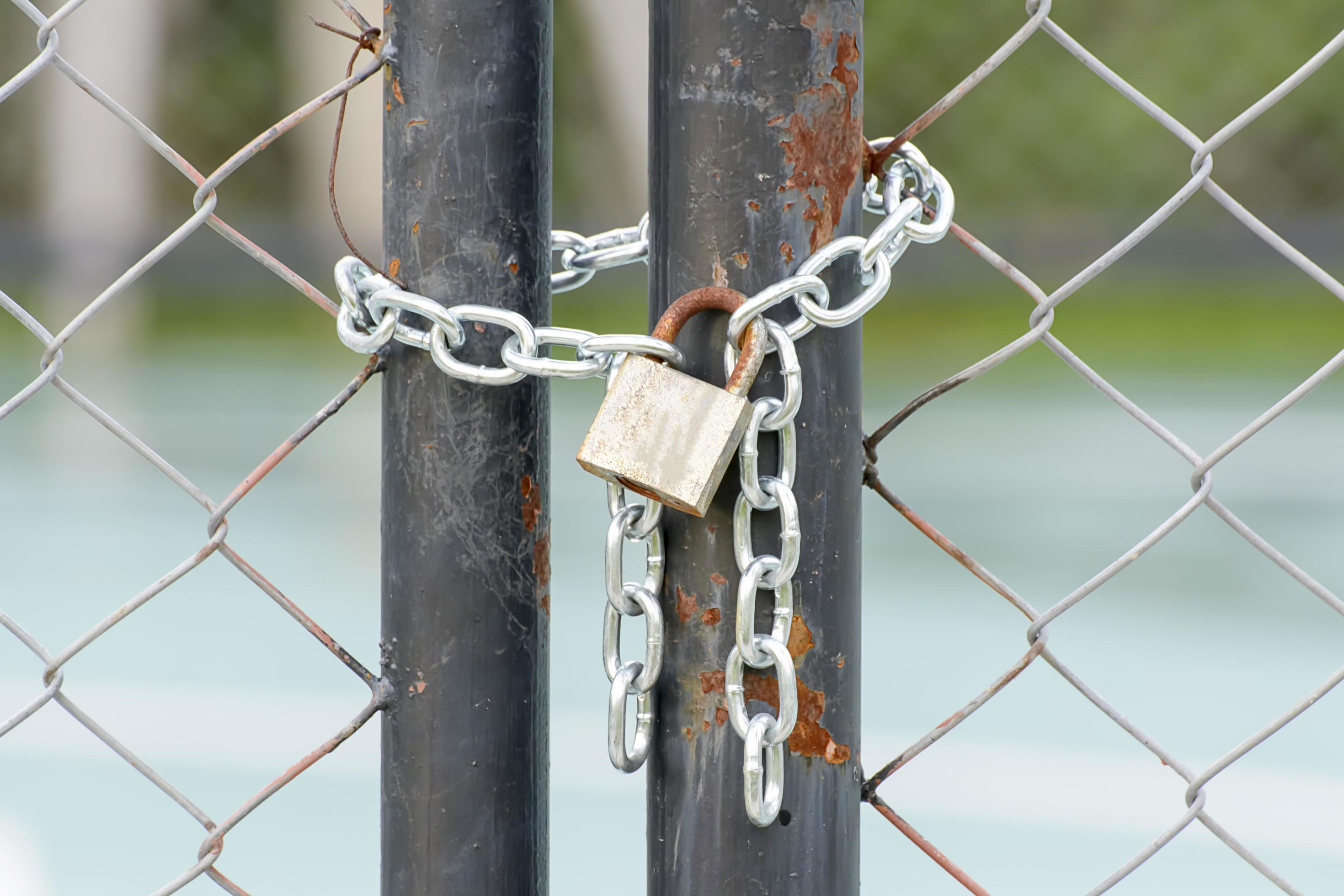 A lock and chain on Metal Fence that links of a gate. 6947802