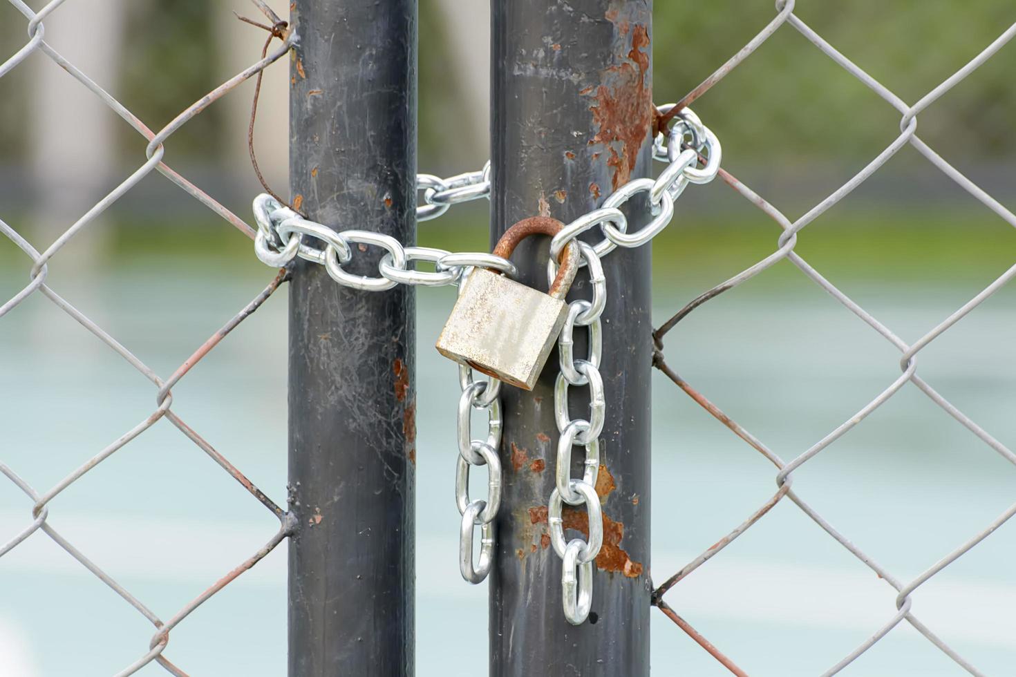 A lock and chain on Metal Fence that links of a gate. photo