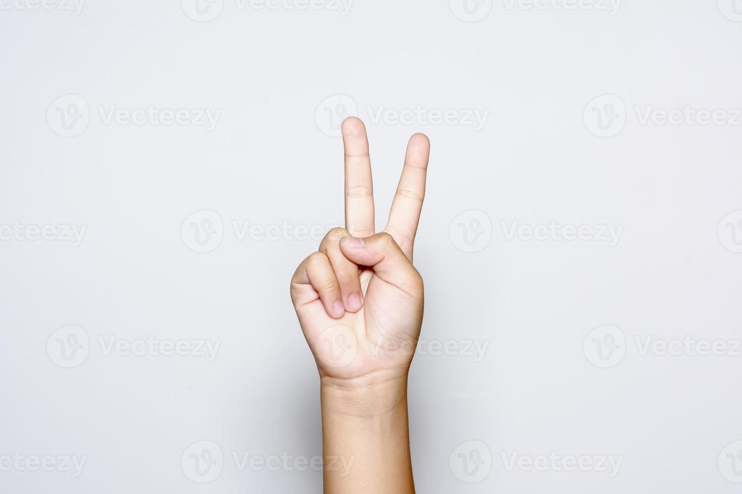 niño levantando dos dedos en la mano muestra lucha de fuerza de paz o símbolo de victoria y letra v en lenguaje de señas sobre fondo blanco. foto