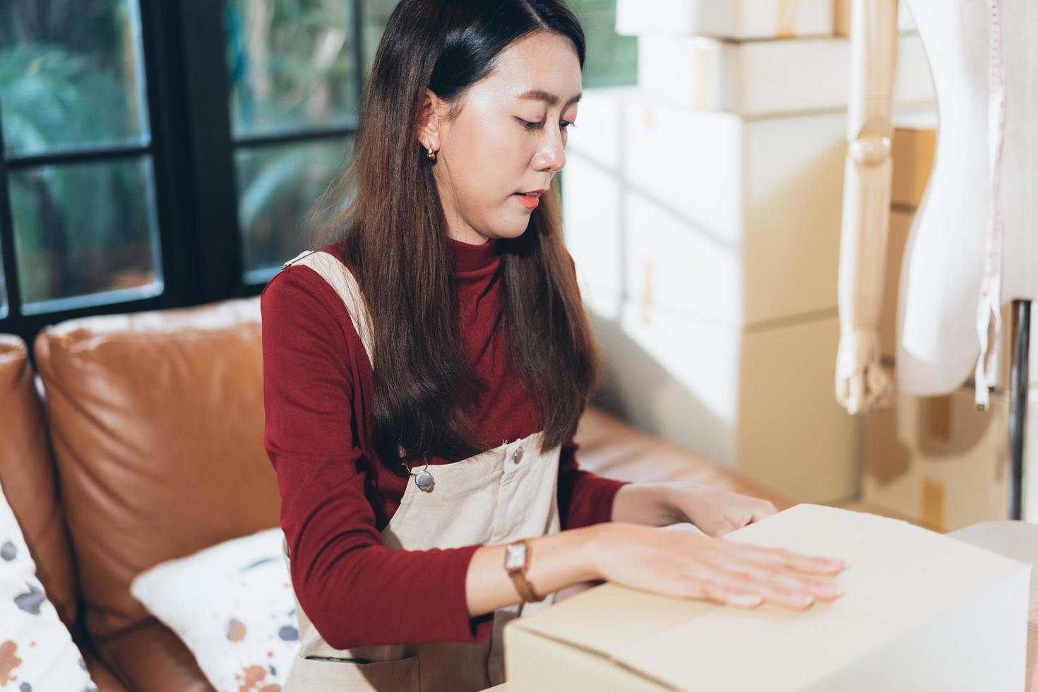 SME small business woman packing and taping carton box. entrepreneur or shop owner working at home. Preparing for delivery, online e-commerce photo