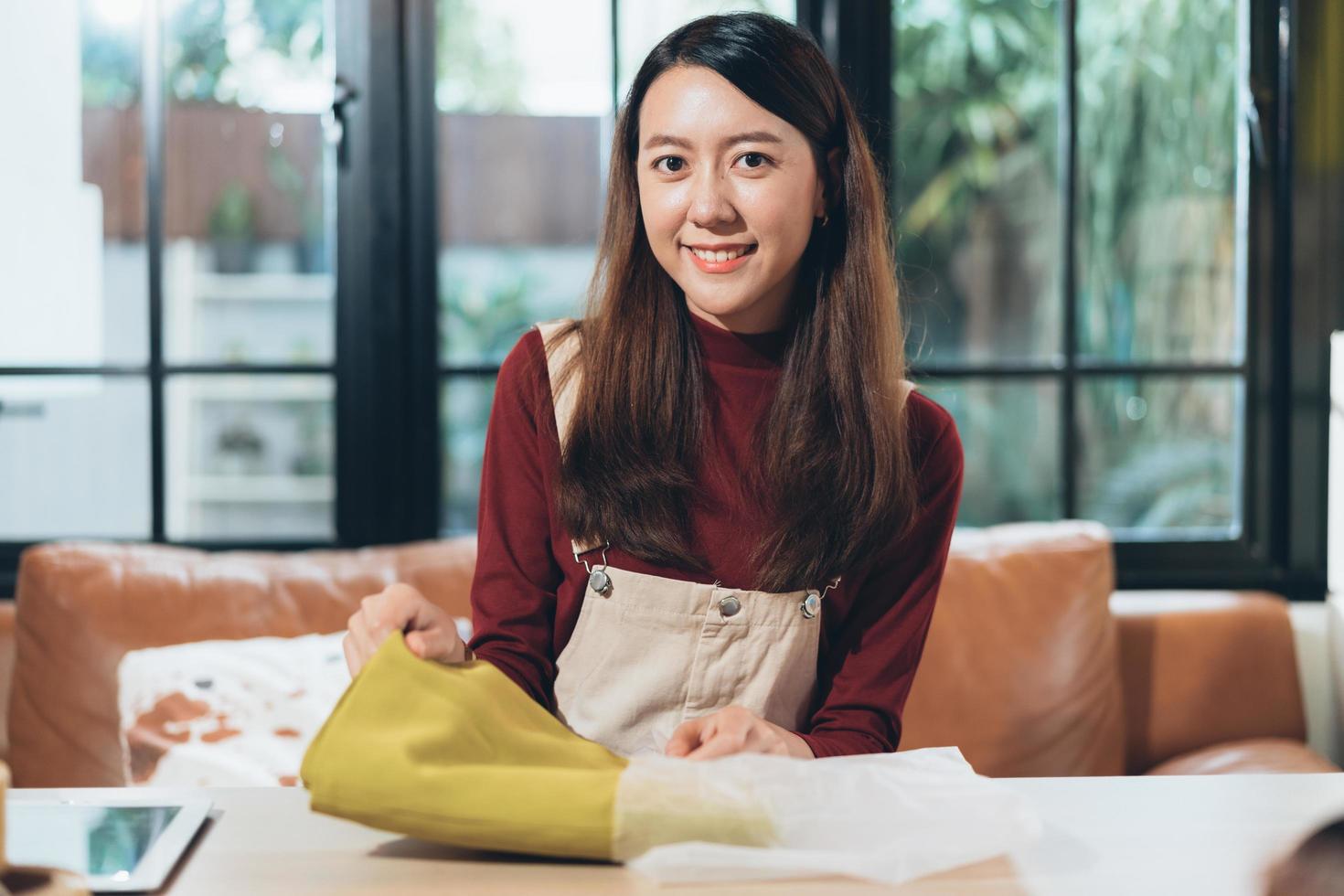 Portrait of SME small business Asian female entrepreneur or shop owner putting cloth into paper packaging to packing customer order preparing before shipping delivery. happy success seller woman. photo