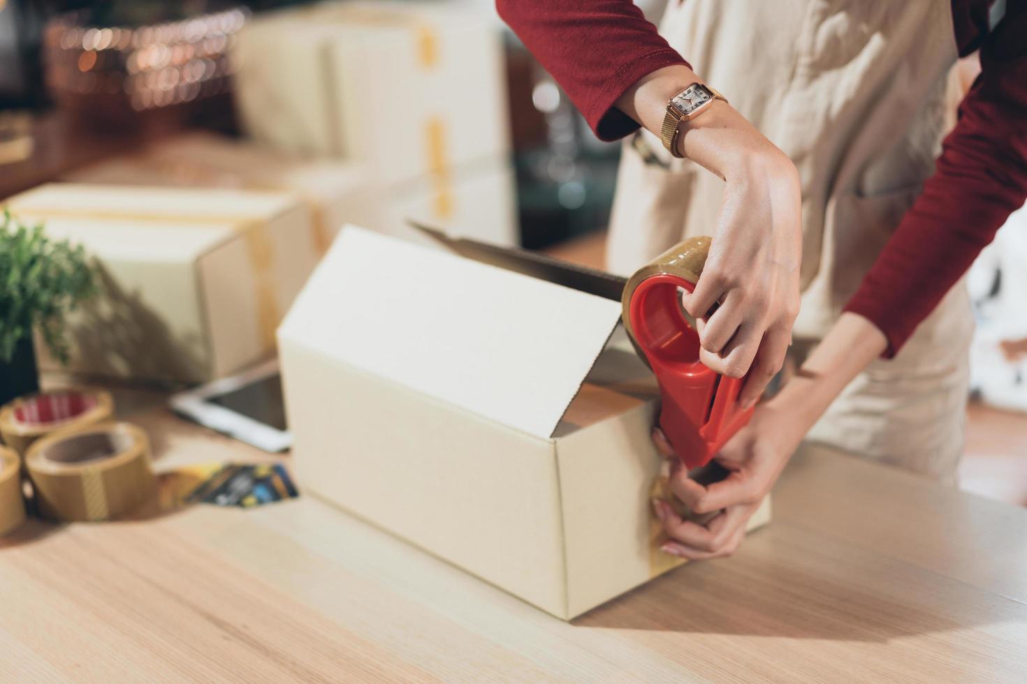 SME small business woman packing and taping carton box. entrepreneur or shop owner working at home. Preparing for delivery, online e-commerce photo