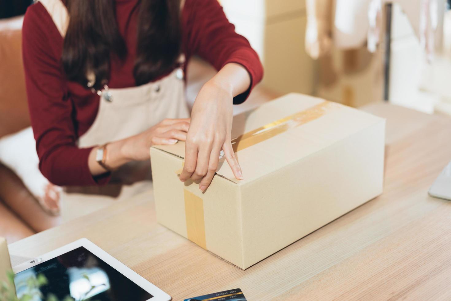 SME small business woman packing and taping carton box. entrepreneur or shop owner working at home. Preparing for delivery, online e-commerce photo