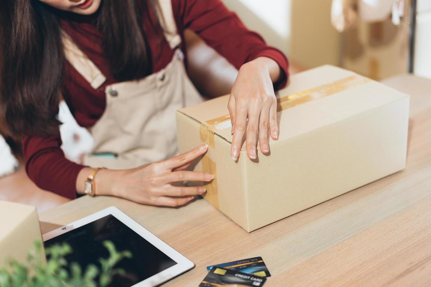 SME small business woman packing and taping carton box. entrepreneur or shop owner working at home. Preparing for delivery, online e-commerce photo