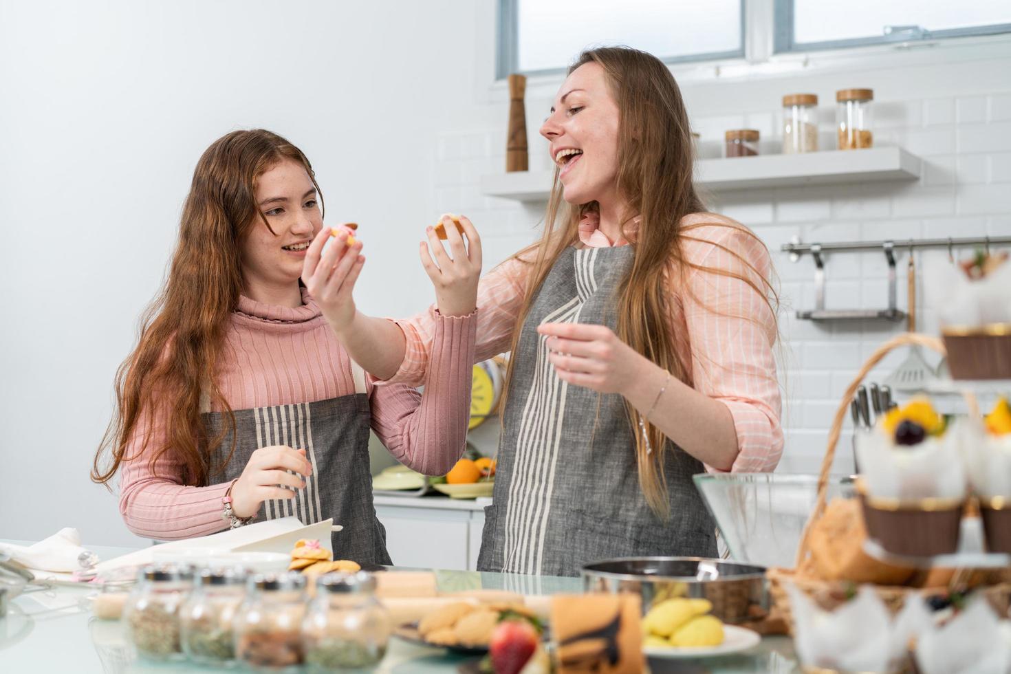 Mother and daughter sharing cookies while baking bakery in the kitchen at home. happy family enjoy preparing dessert together. photo