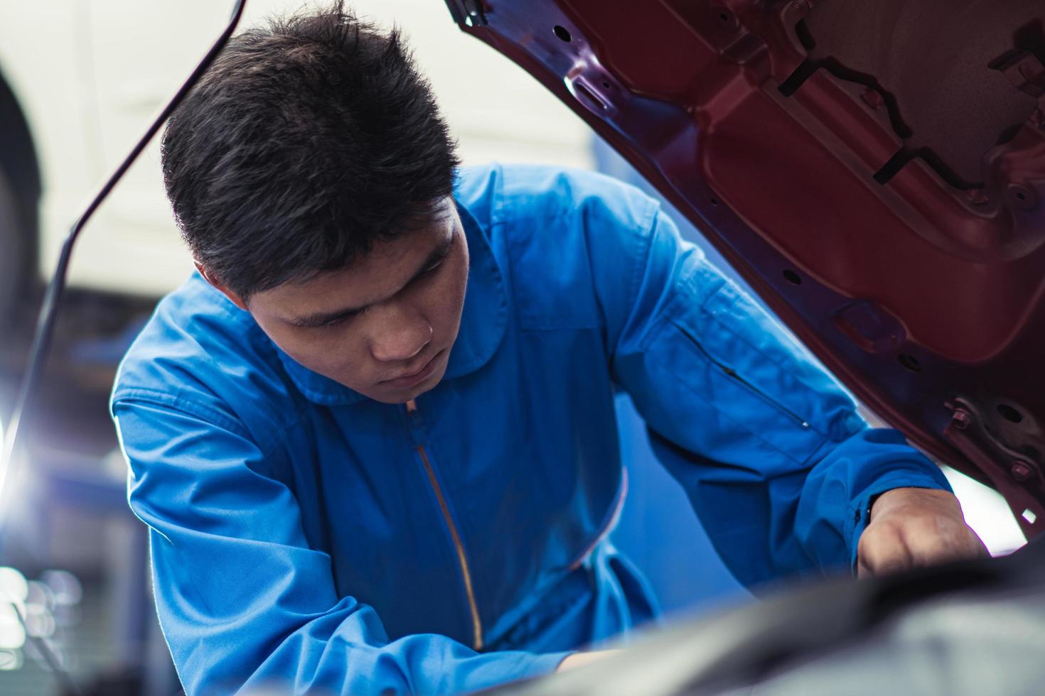 Asian automobile mechanic man checking car damage broken part  condition, diagnostic and repairing vehicle at garage automotive, motor technician maintenance after service concept photo