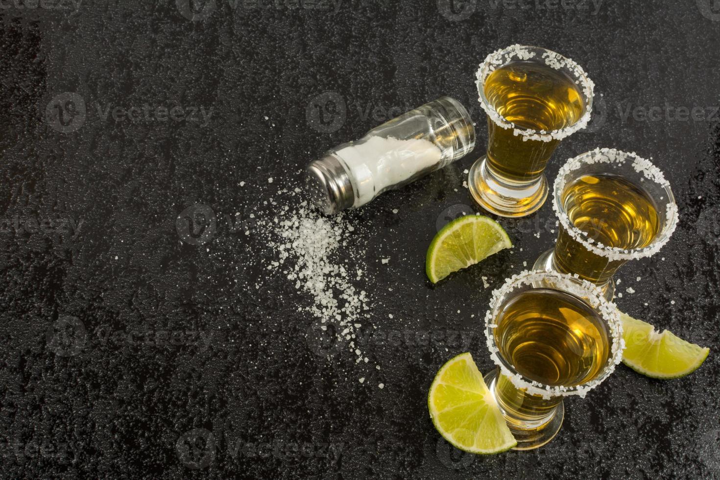 Gold tequila with lime on black background, top view photo