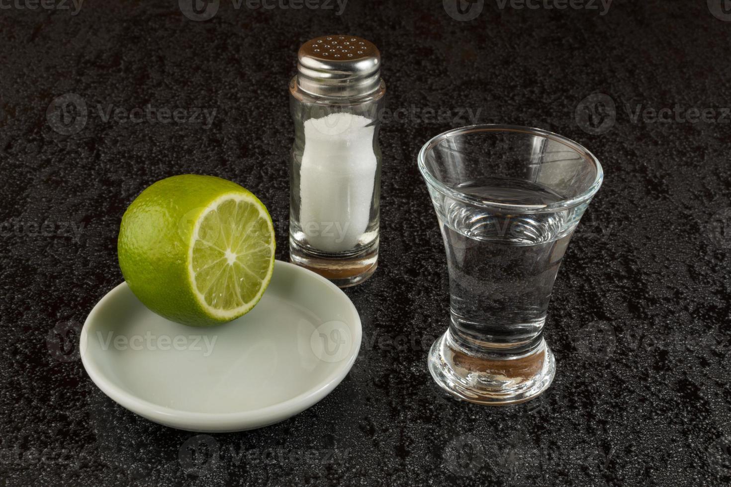 tequila plateado con limón sobre fondo negro foto