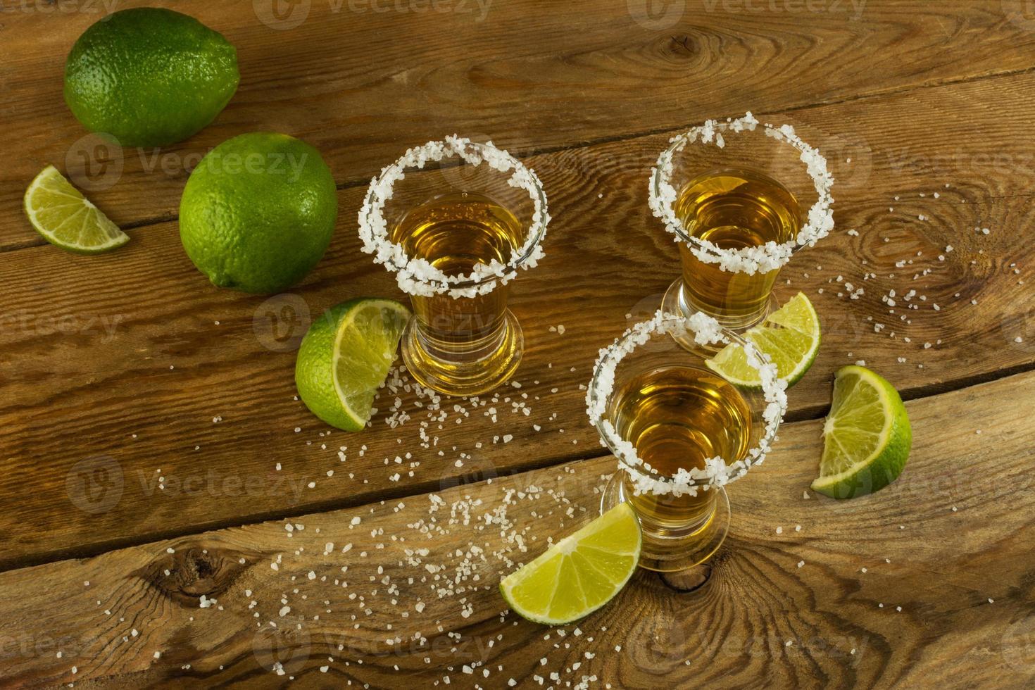 Tequila shots with lime and salt on the wooden background top view photo