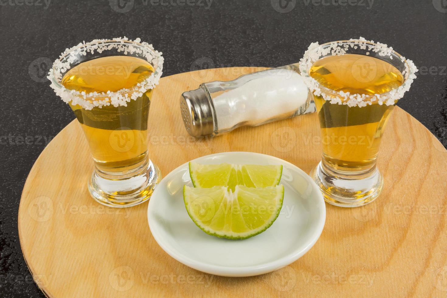 Shots of gold tequila on the wooden tray photo