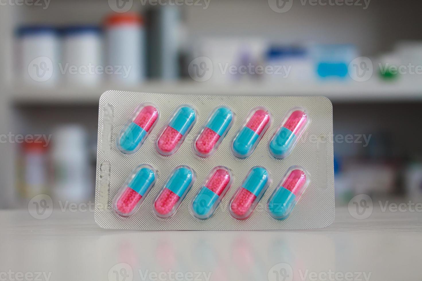 colorful capsules pills with blur shelves of drug in the pharmacy drugstore background photo