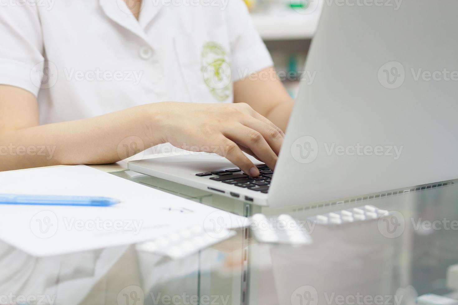 Pharmacist with laptop computer and medication in the pharmacy photo