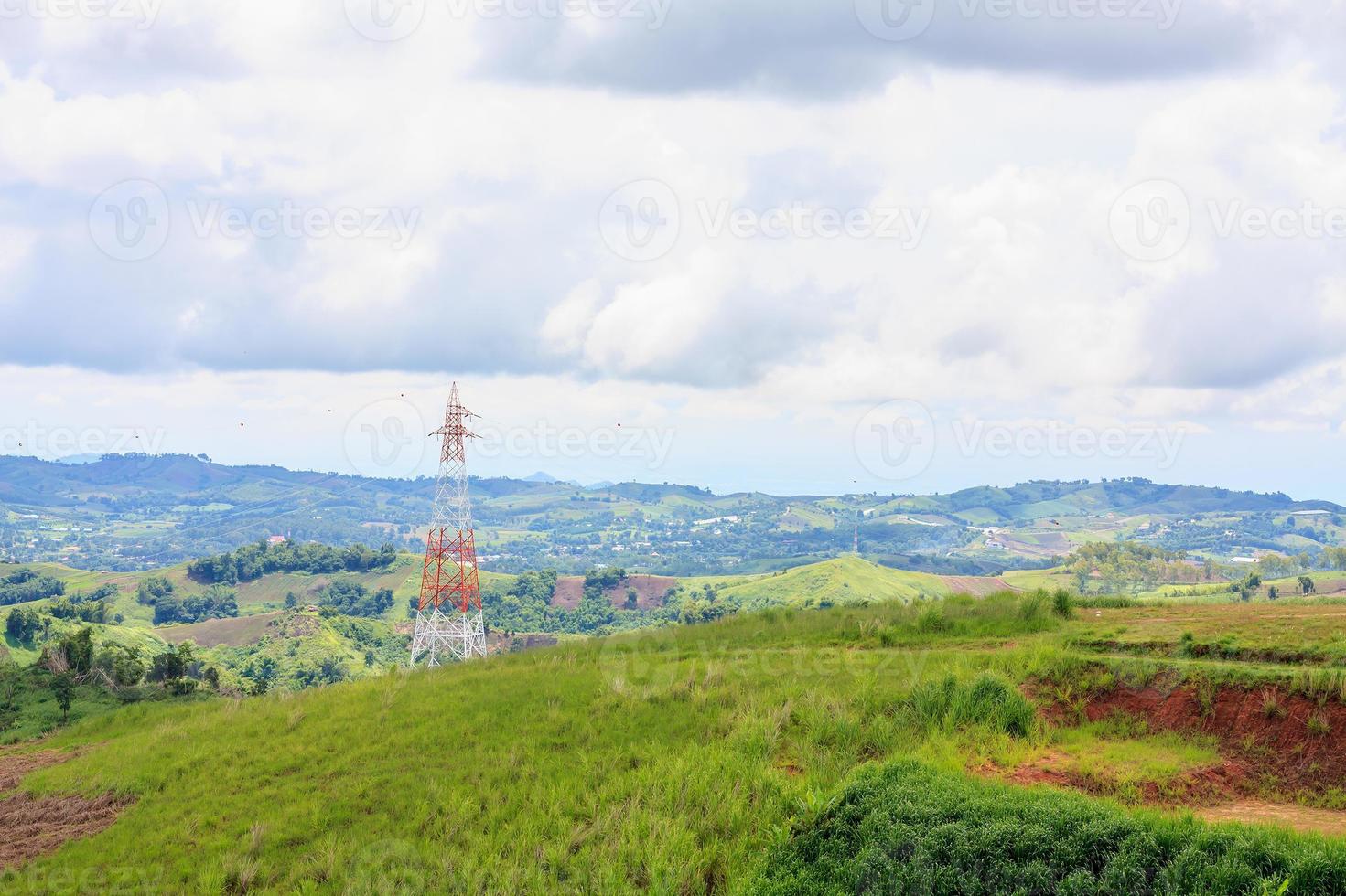 High voltage power lines tower on green mountain photo