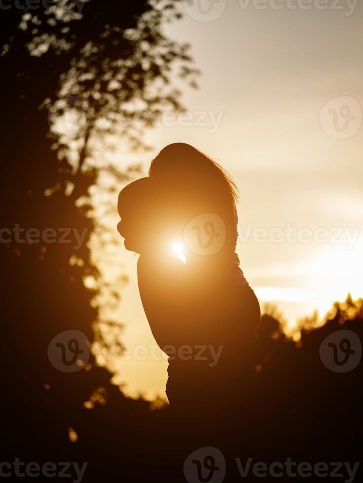 silhouette of lovers embracing on the background of the sunset photo