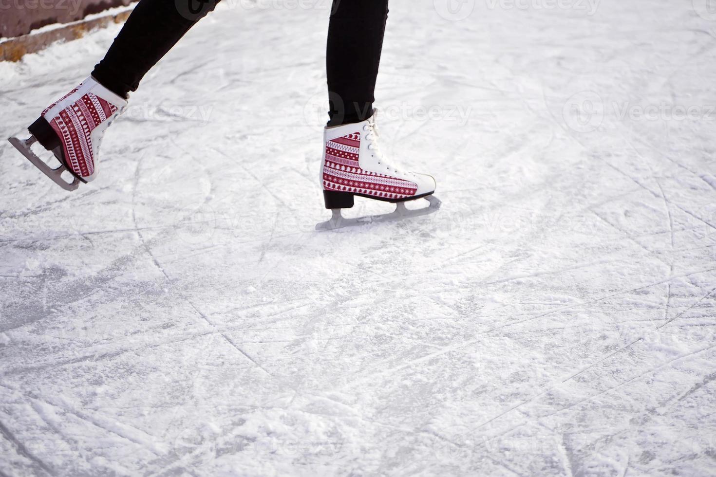 Girl riding on an ice rink. Ice and skates. Man's feet in skates photo