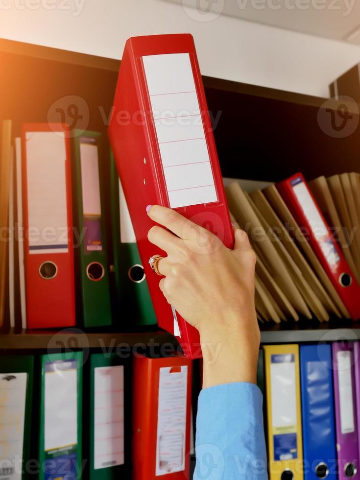 the girl in the archive puts a folder with documents on the shelf close-up photo