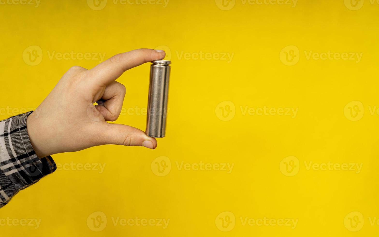 battery in hand close up on a yellow background photo