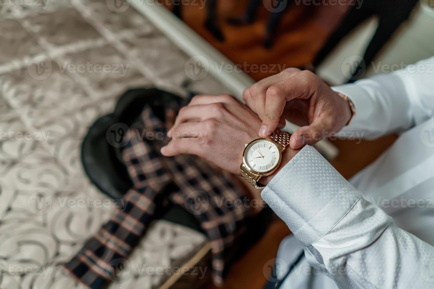 un hombre se pone un reloj de oro de cerca. foto