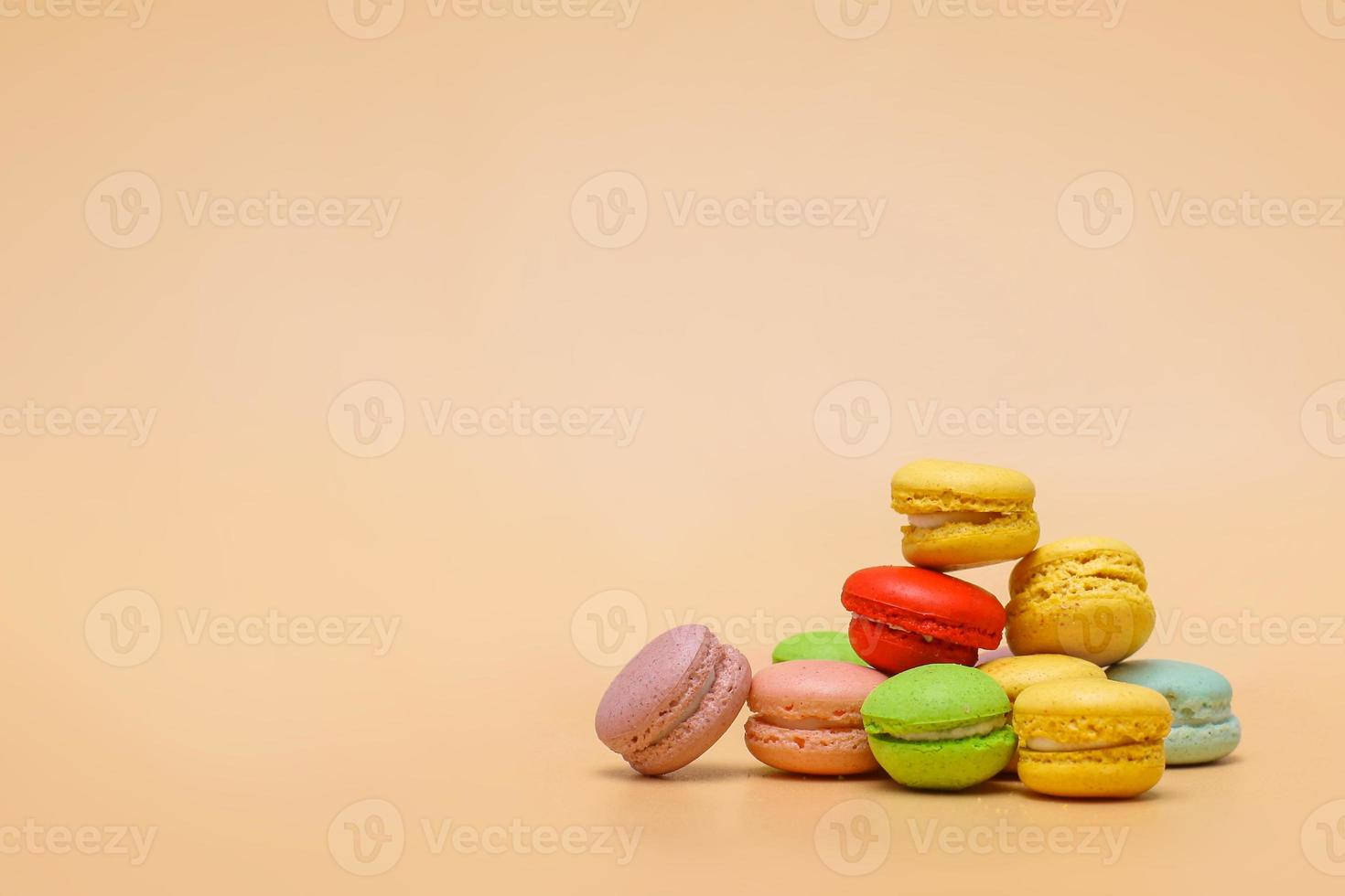 Stack of colorful macarons on cream colored background with copy space photo