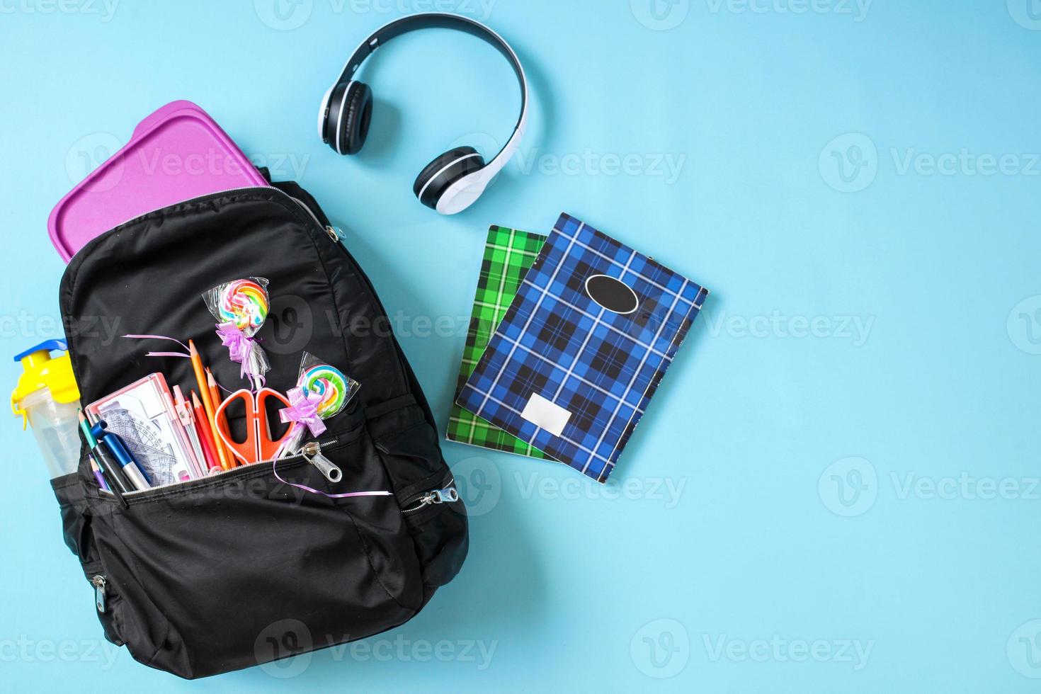 Creative flat lay School bag with school supplies on blue background for back to school concept photo