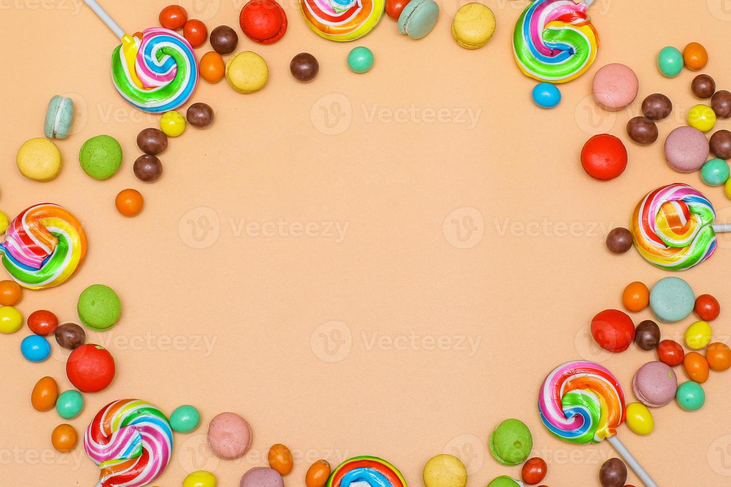 Blank circular frame made with various of colorful candy on cream background. Flat lay, top view photo