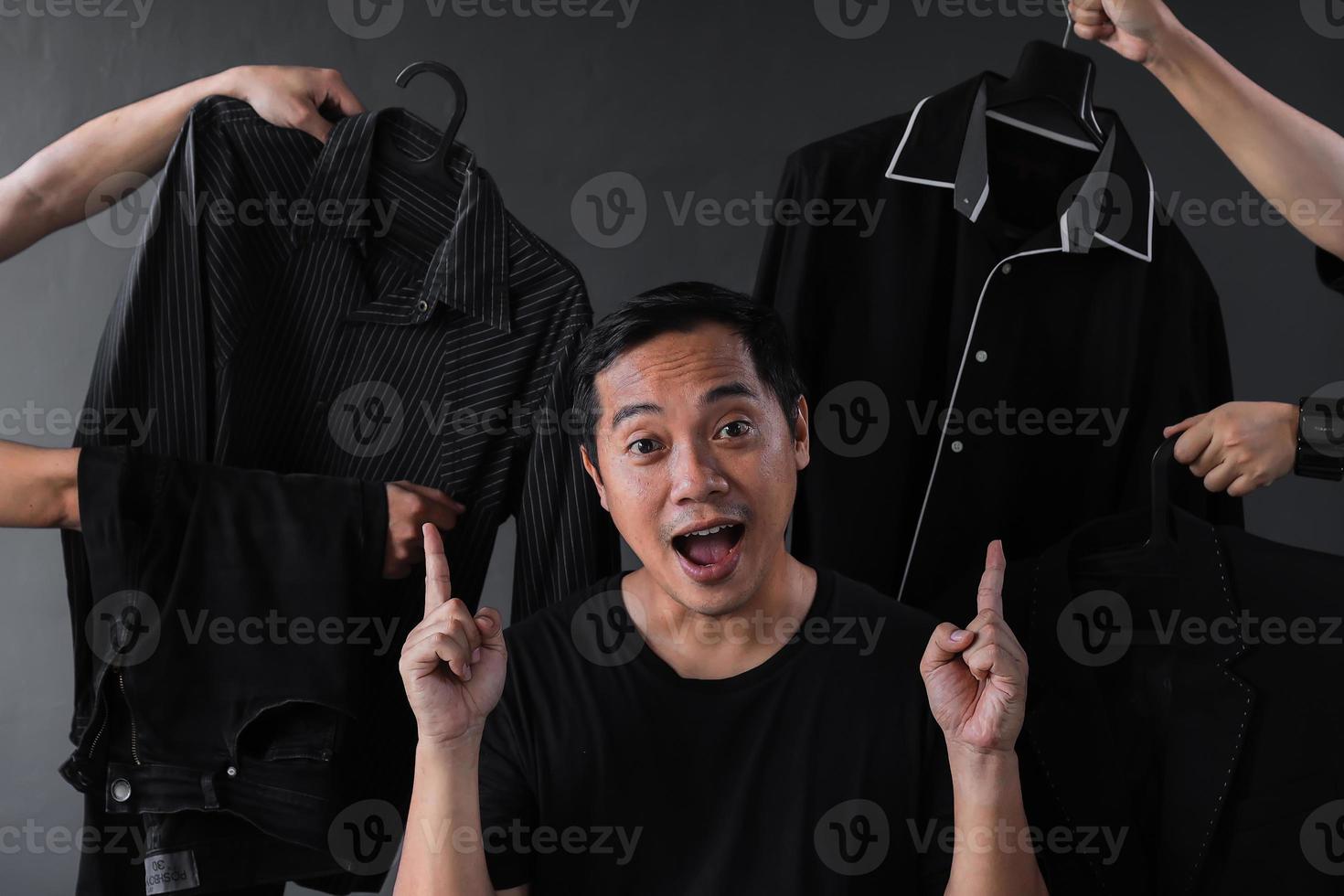 hombre adicto a las compras rodeado de muchas manos sosteniendo ropa de hombre para el concepto de promoción de ventas de tiendas de moda foto